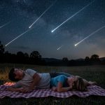 Une famille allongée sur une couverture en pleine nuit d’août observe un ciel étoilé avec plusieurs étoiles filantes au-dessus d’un paysage sombre.