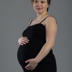 Femme enceinte posant simplement dans un studio photo lumineux.