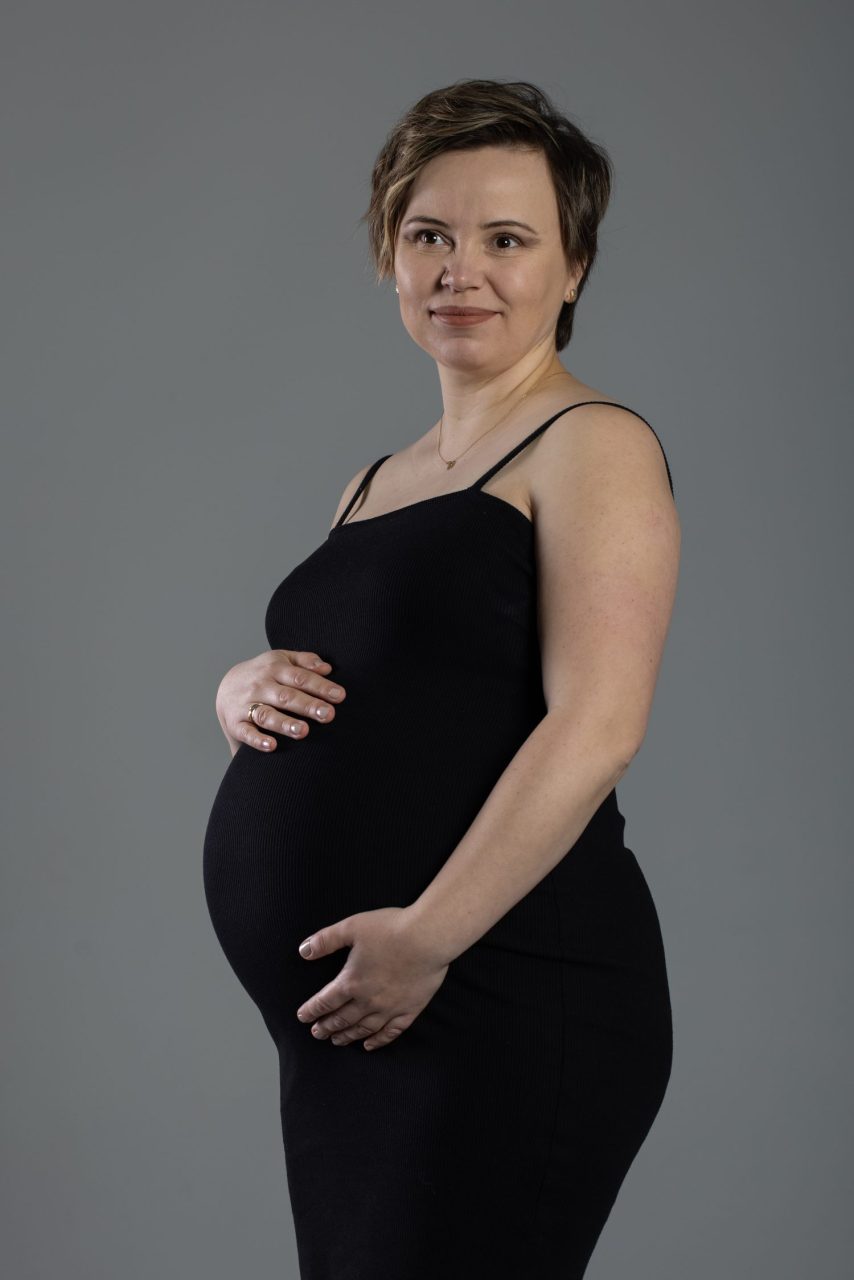 Femme enceinte posant simplement dans un studio photo lumineux.